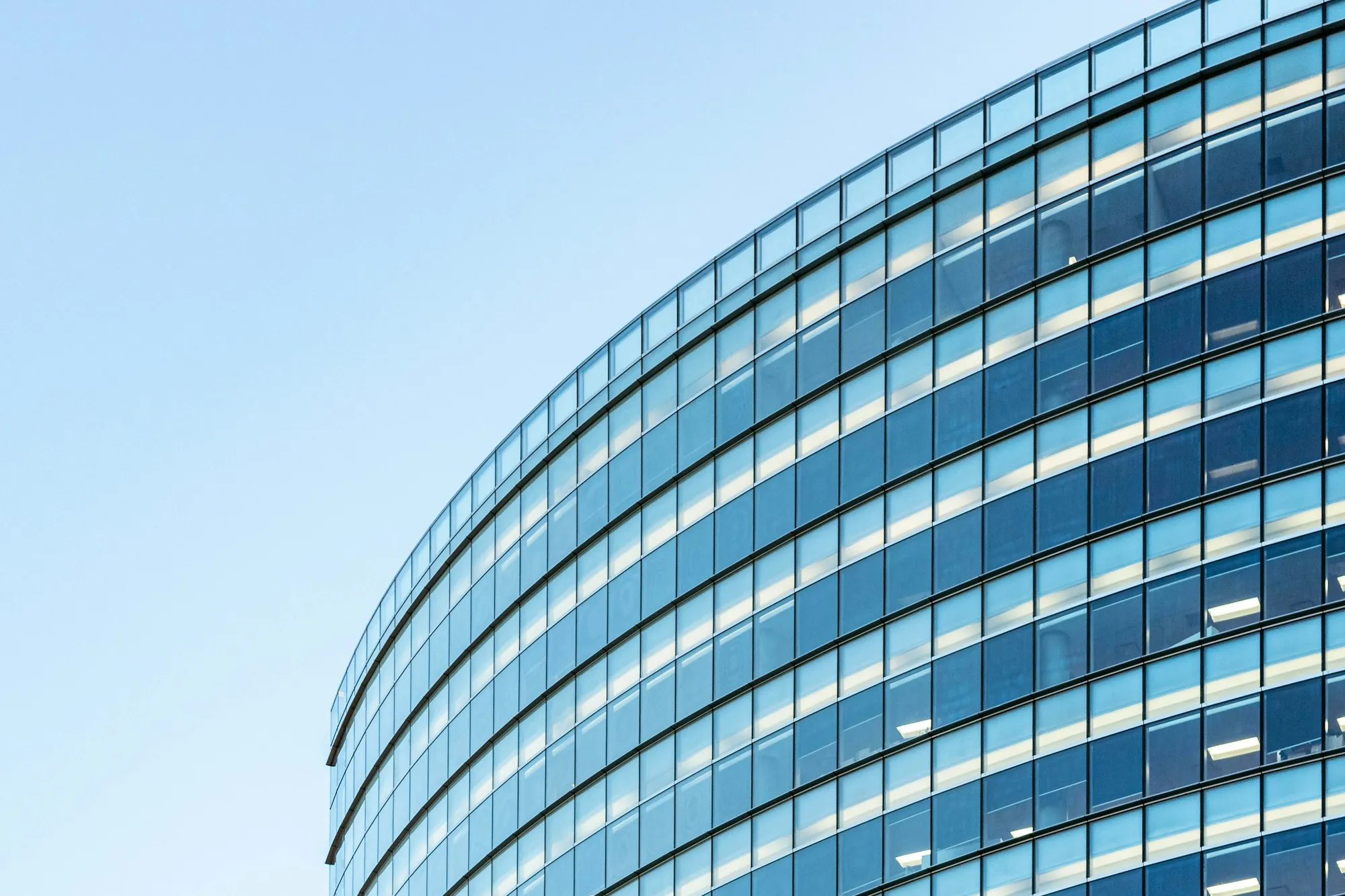 Curved glass office building facade, illustrating NNN vs gross vs modified gross commercial leases for Farmersville businesses