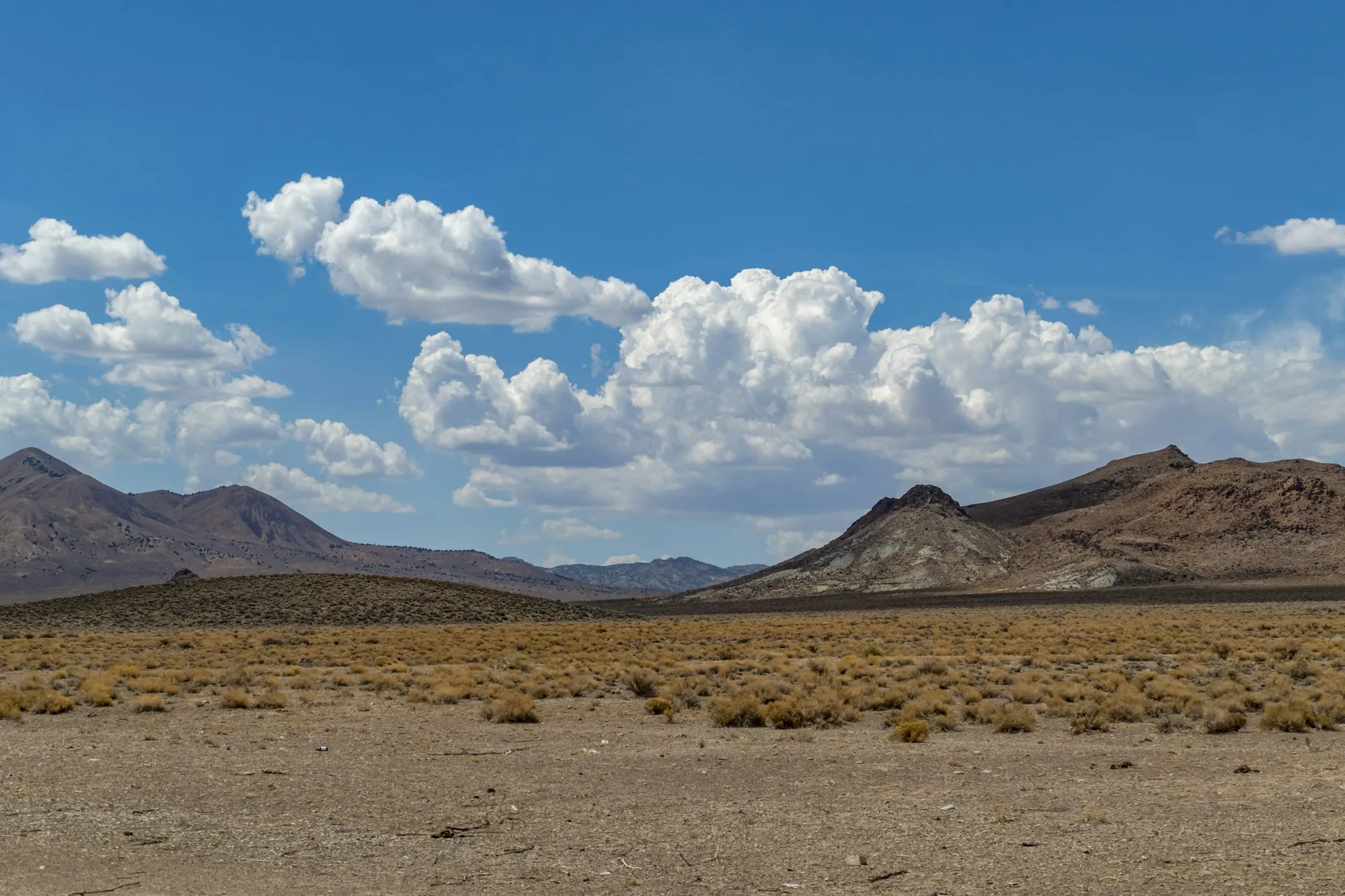 Desert valley with mountains and puffy white clouds