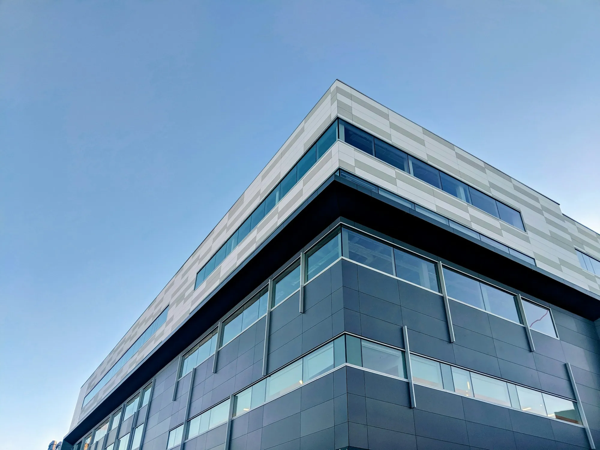 Office building corner with glass bands under blue sky