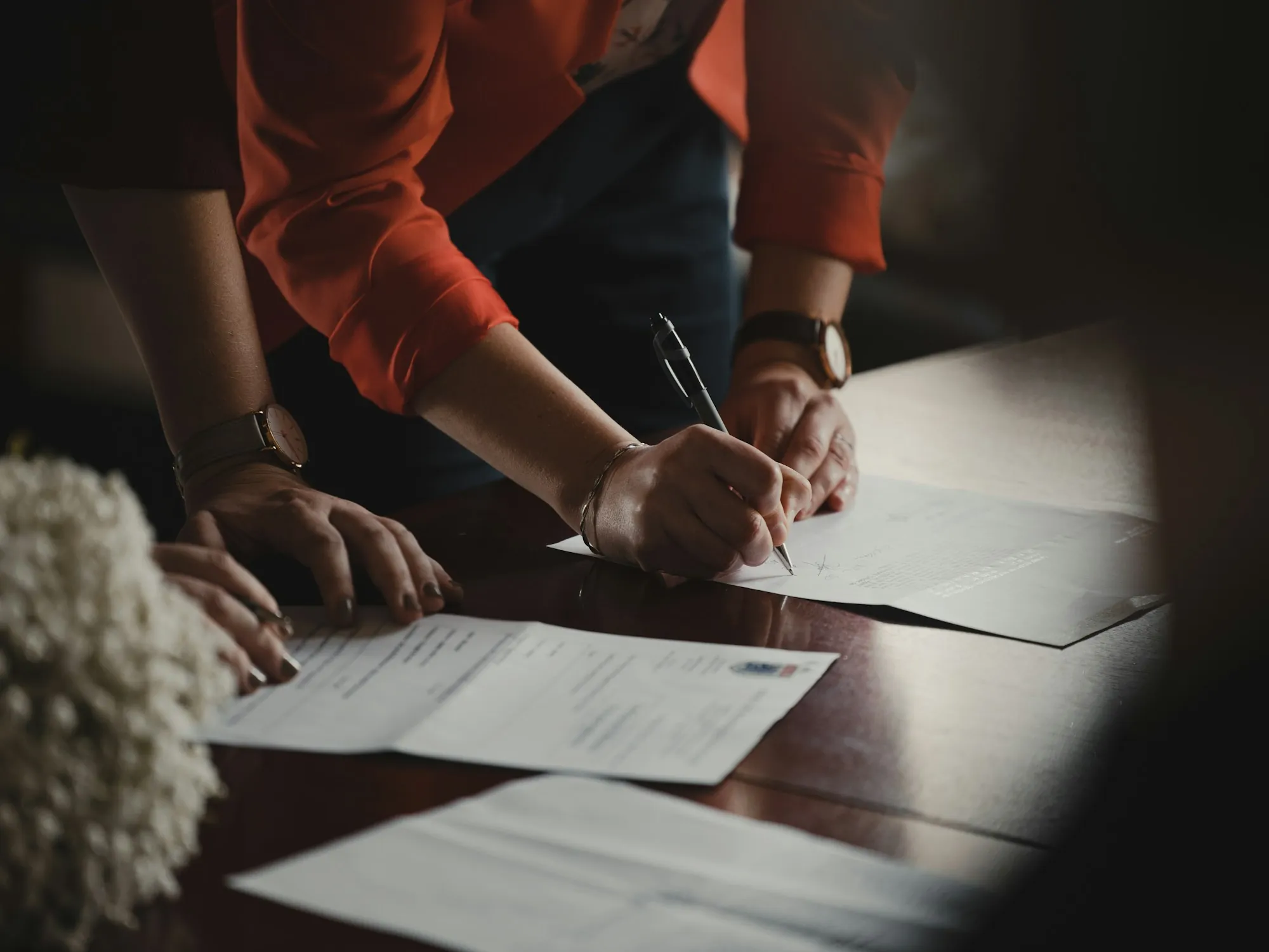 Two people signing papers at a wooden table