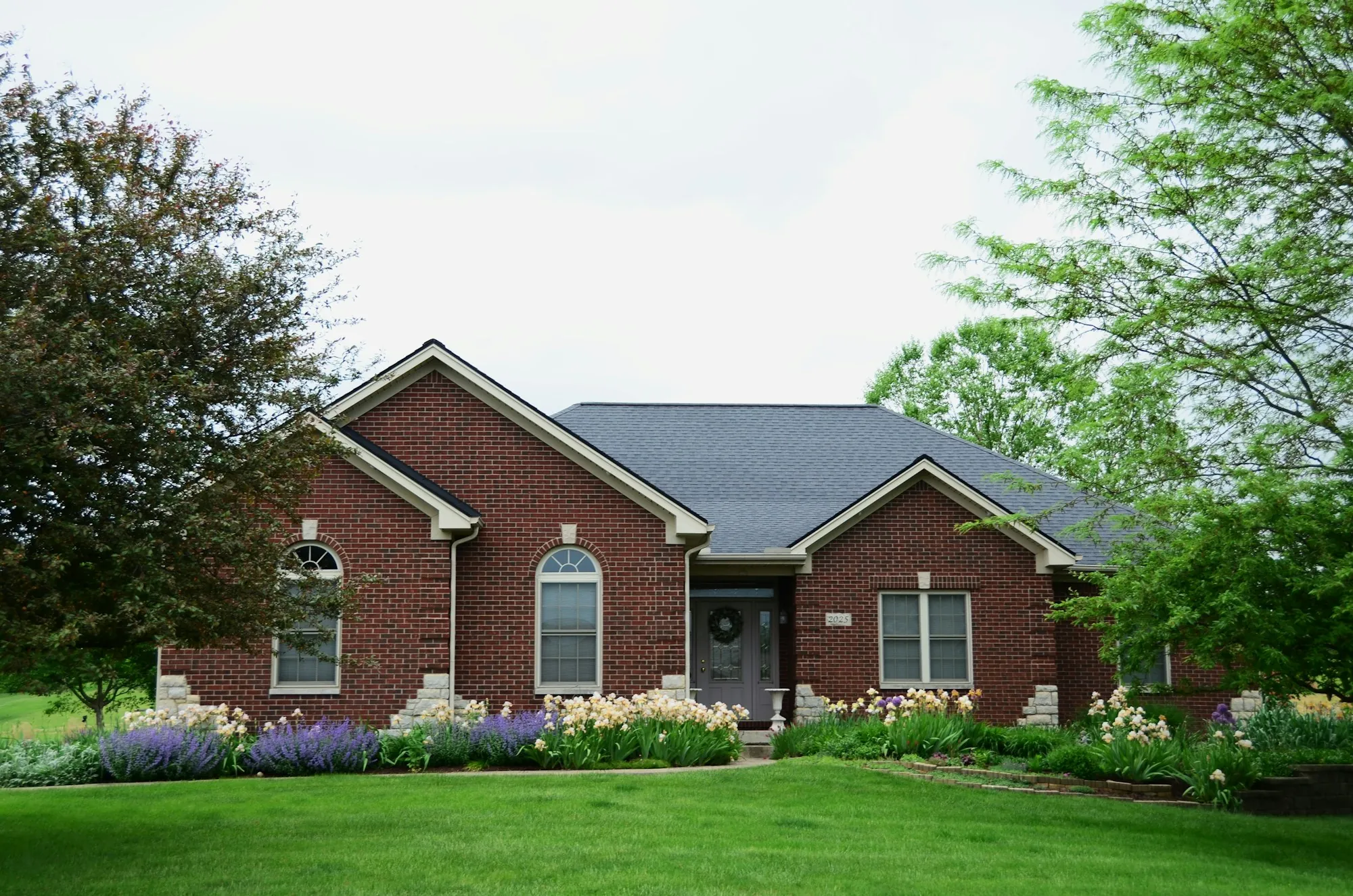 Brick single-story house with arched windows and a green lawn